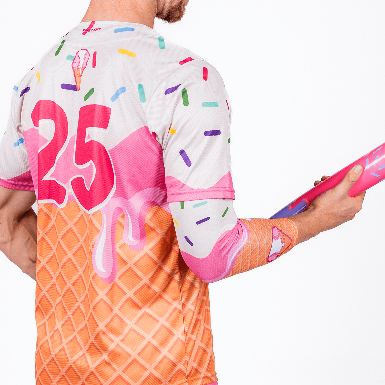 Person wearing a colorful ice cream-drip baseball shirt with the number 25, holding a pink object.