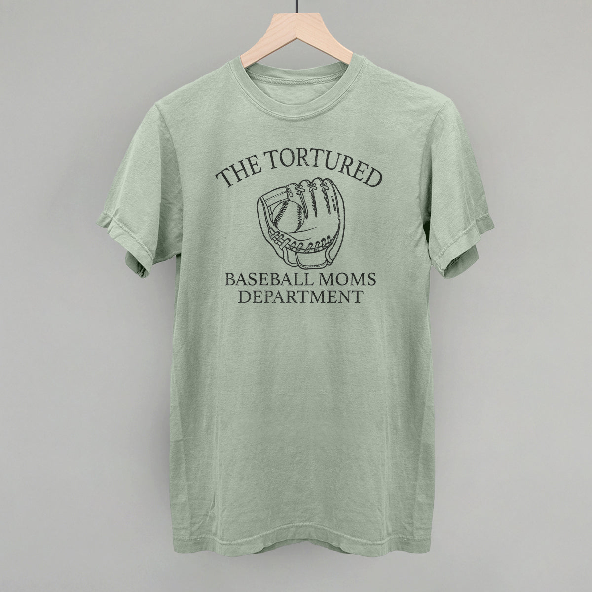 Green t-shirt with 'The Tortured Baseball Moms Department' graphic on a hanger against a gray background