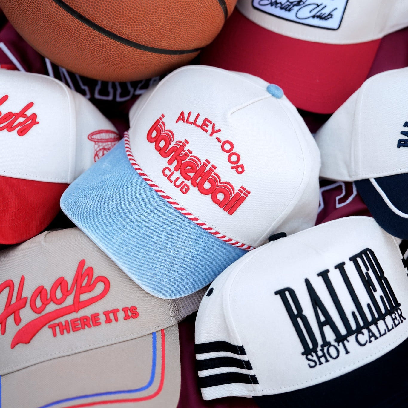 Collection of sports-themed hats and a basketball on a colorful background