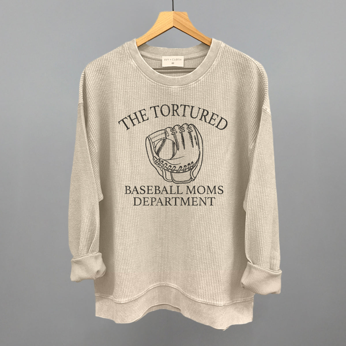 Collection of Beige sweatshirt with graphic and with 'The Tortured Baseball Moms Department' text on a hanger against a gray background in a gallery layout