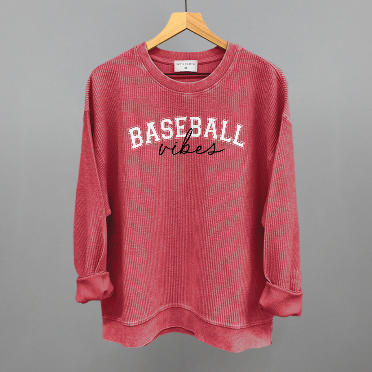 Red sweatshirt with 'BASEBALL vibes' text on a hanger against a gray background