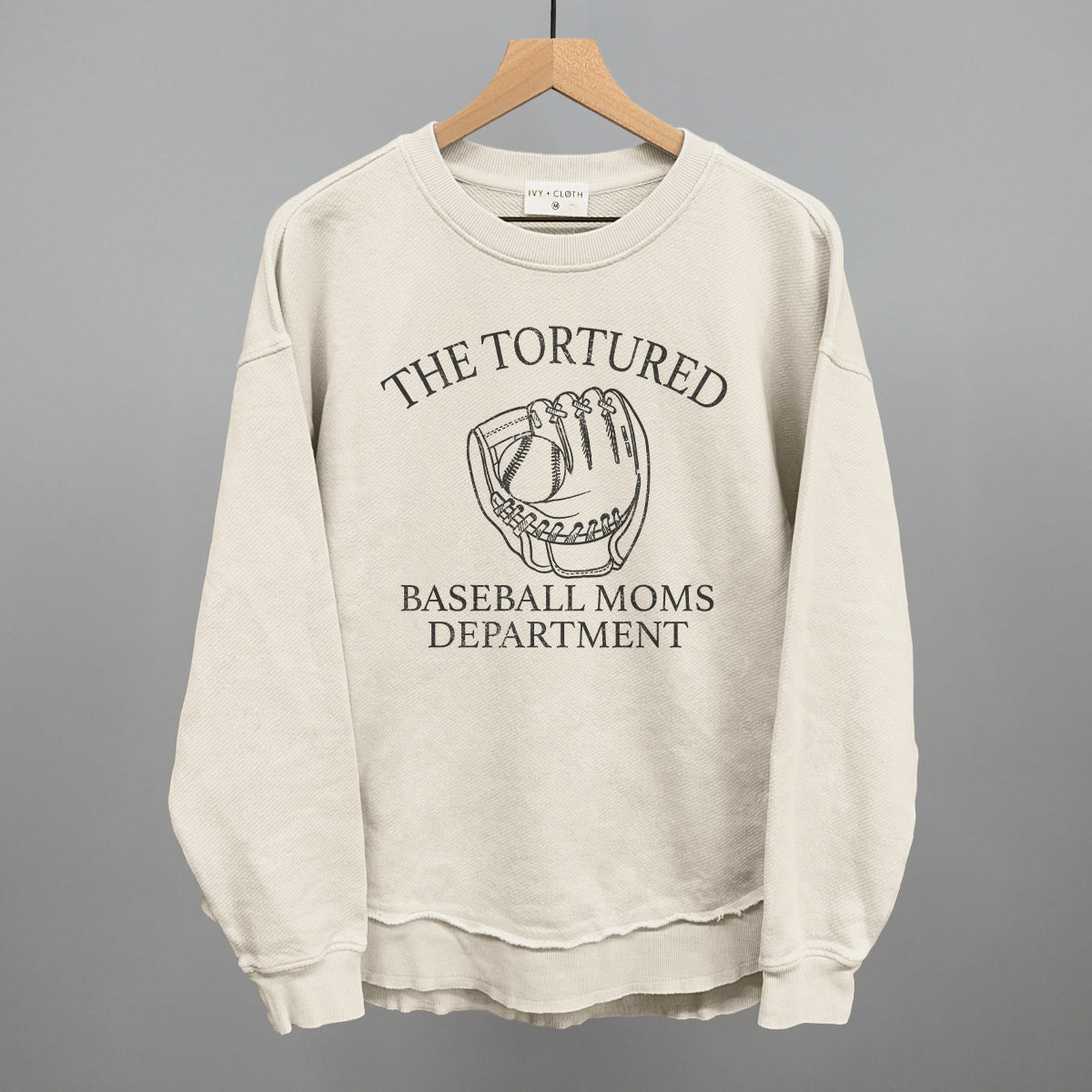 Collection of Beige sweatshirt with 'The Tortured Baseball Moms Department' text and graphic on a hanger against a gray background in a gallery layout