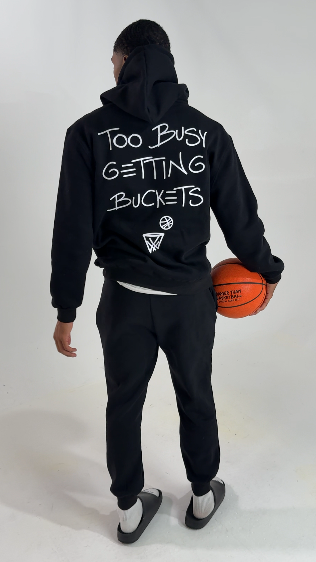Collection of Person wearing a black hoodie with text and holding a basketball on a white background in a gallery layout