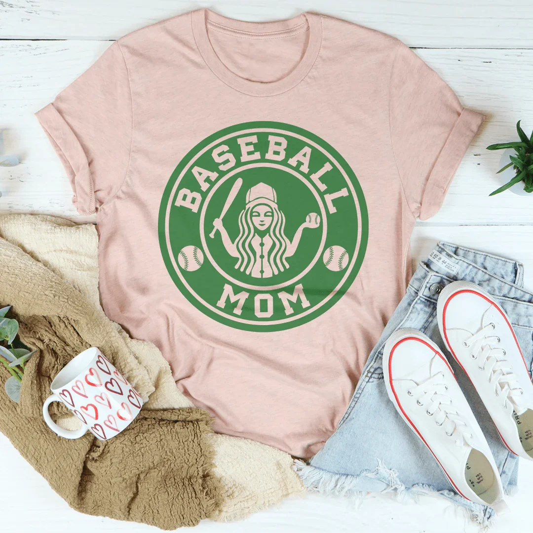 Pink t-shirt with 'Baseball Mom' graphic design on a white surface with accessories.
