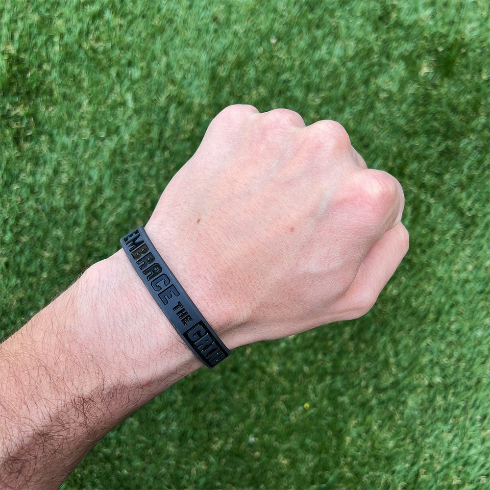 Collection of Hand wearing a black wristband with text on a green grass background in a gallery layout