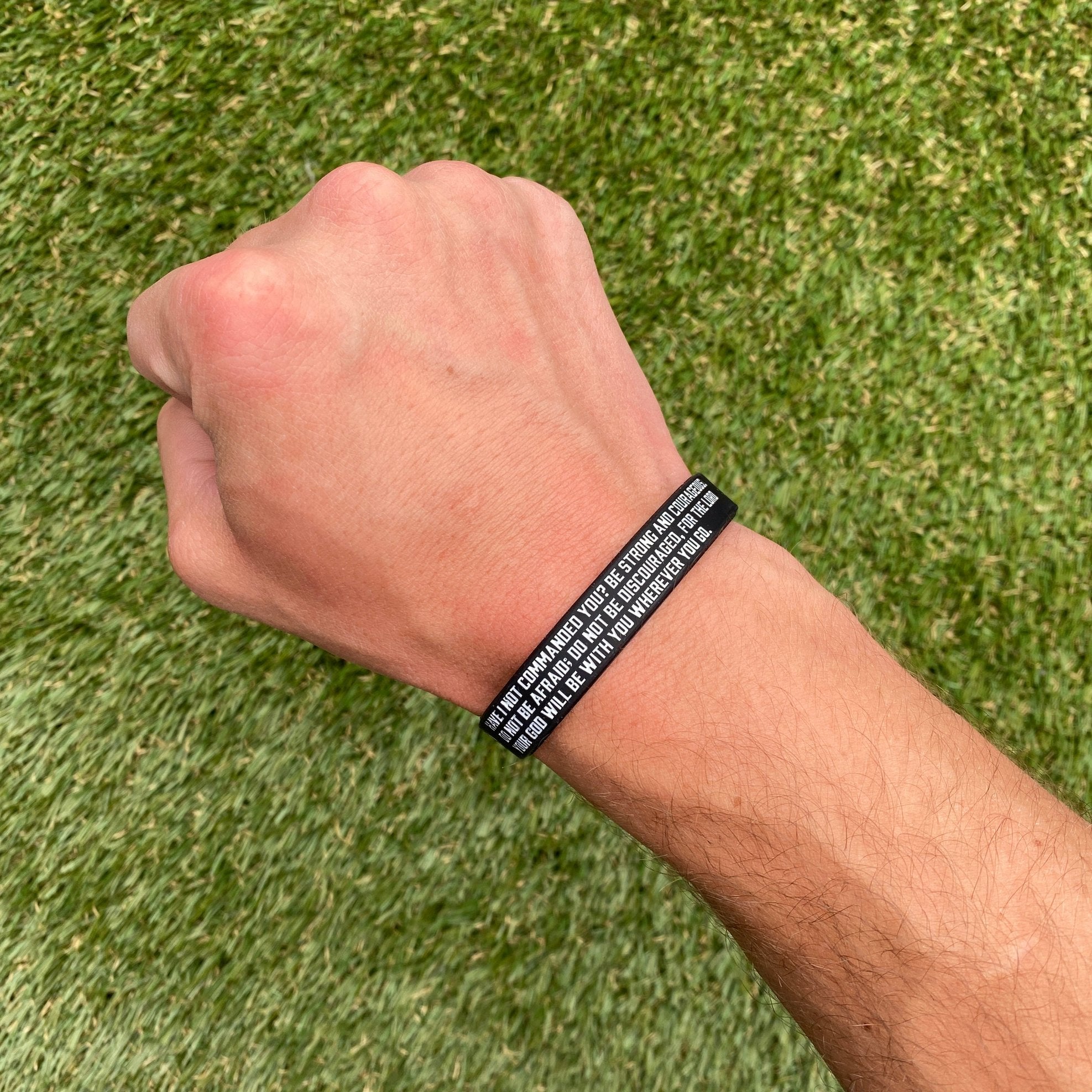 Collection of Black wristband with text on a wrist against a grass background in a gallery layout