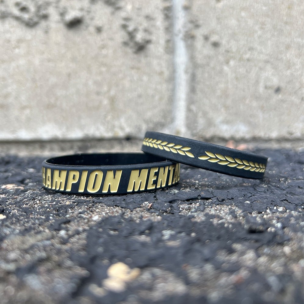 Black wristbands with gold text on a textured surface