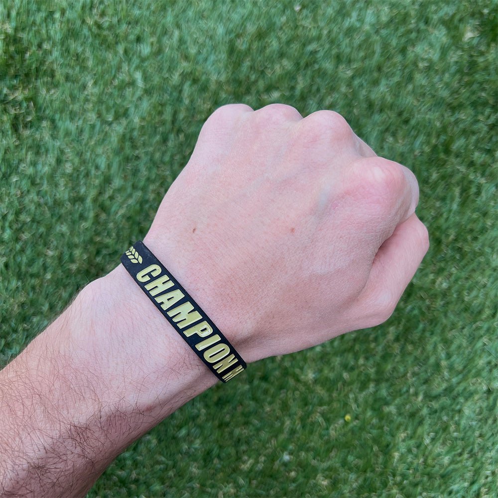 Hand wearing a wristband with 'CHAMPION' text on a grass background