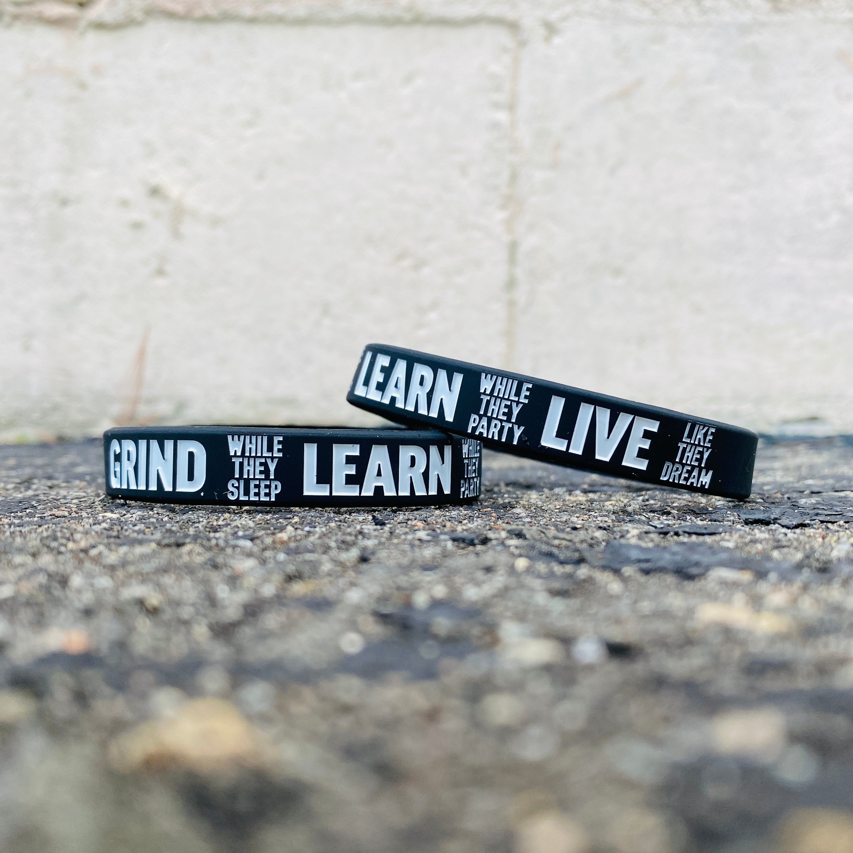 Collection of Black wristbands with motivational phrases on a concrete surface. in a gallery layout