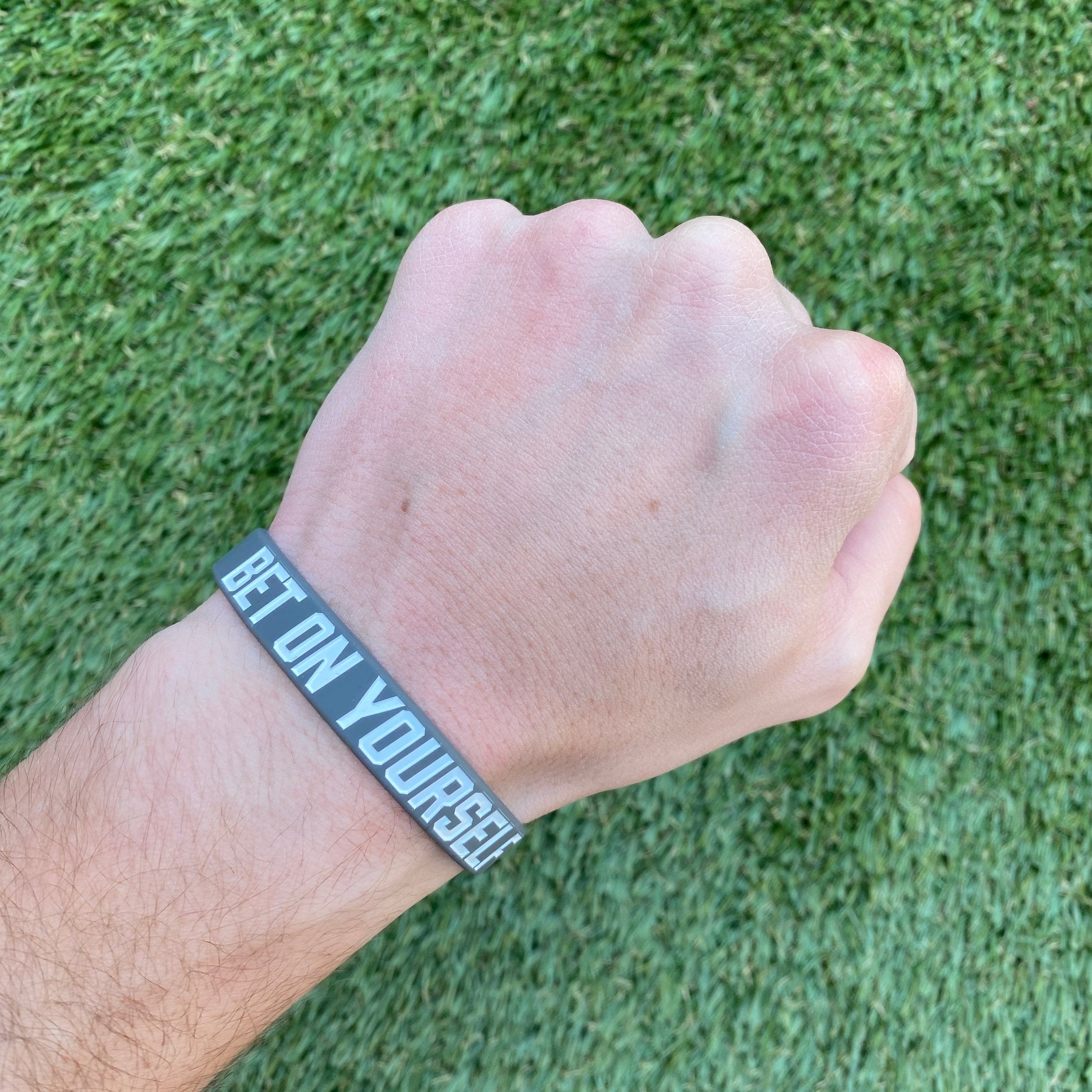 Collection of Hand wearing a bracelet with 'Believe in Yourself' on a grass background in a gallery layout